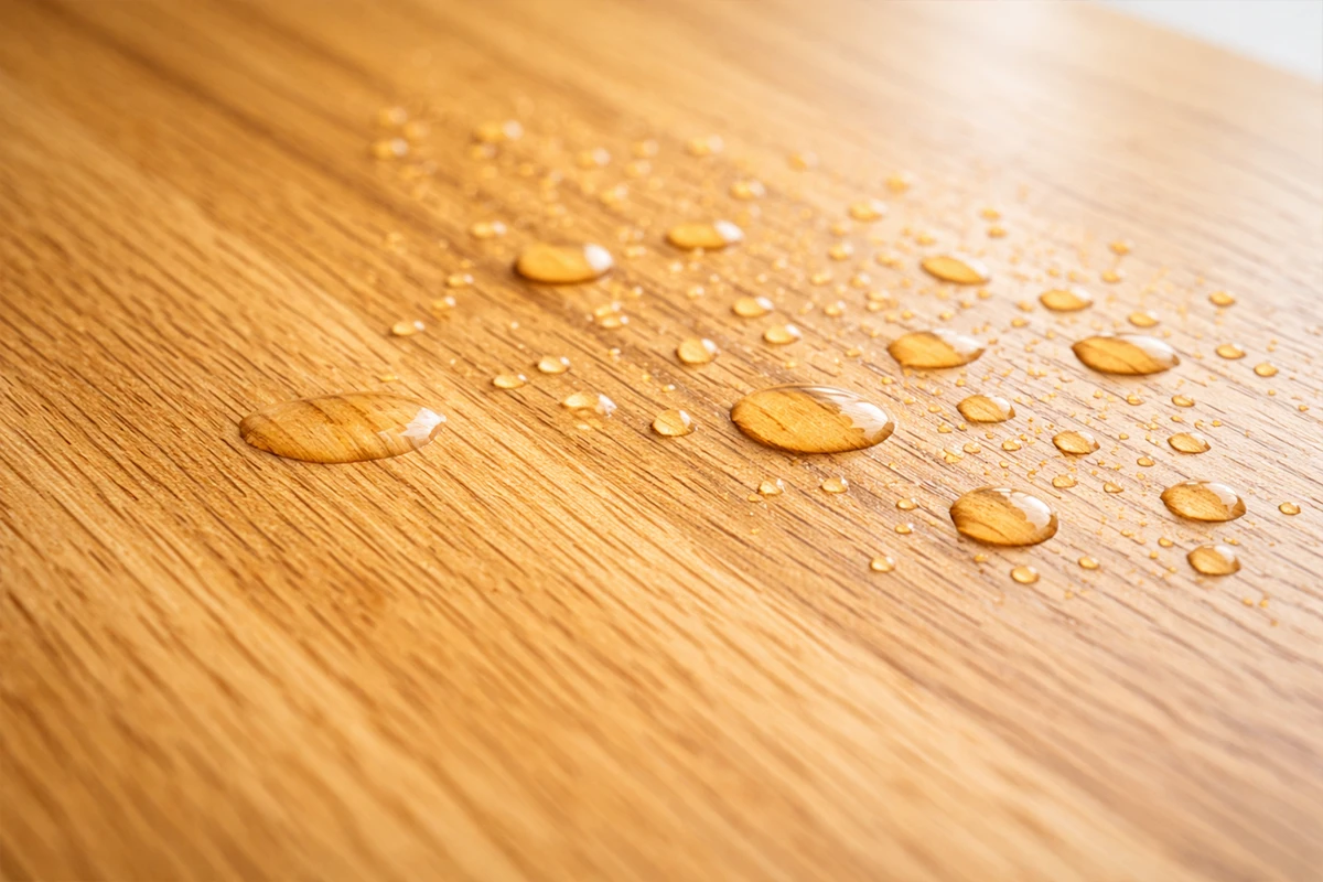 Wassertropfen auf geölter Buchenholzoberfläche zeigen den Schutz durch Schönbuch Holzöl vor Feuchtigkeit und Wasserflecken